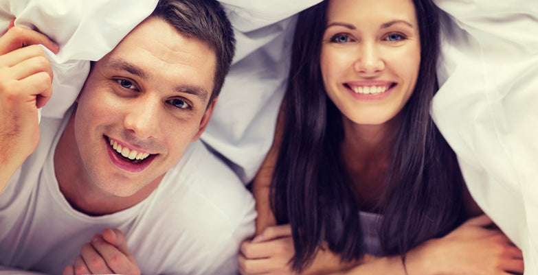 Couple in bed together under the sheets