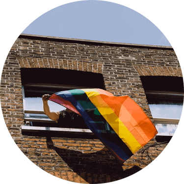 Person waving Pride flag from window