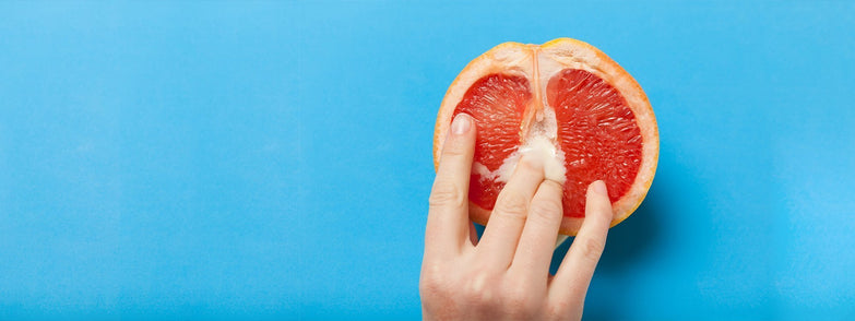 Person keeping fingers in centre of half sliced orange.