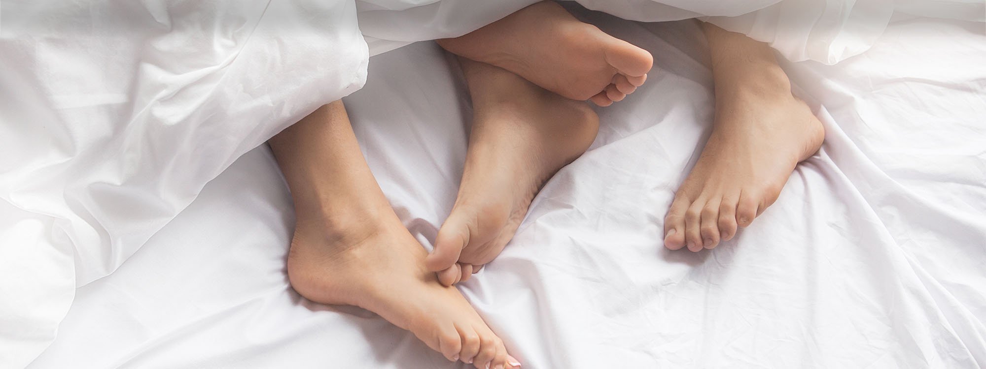 Couples legs displaying in Bed.