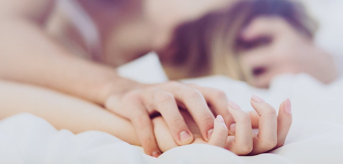 couple holding hands on bed